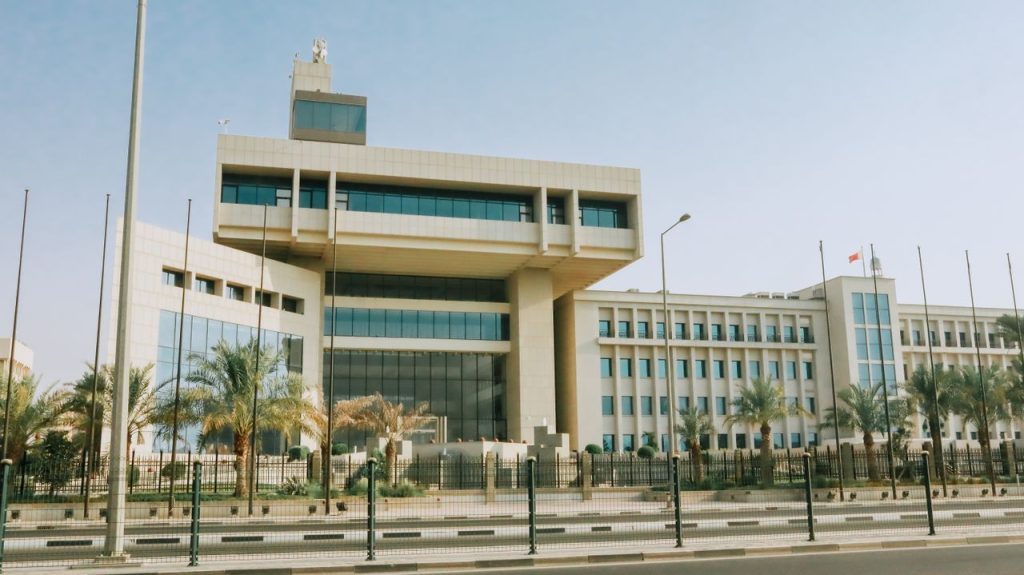 Modern office building with palm trees under a clear sky.
